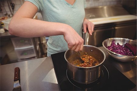 simsearch:614-06895771,k - Midsection of young female chef cooking food in commercial kitchen Photographie de stock - Premium Libres de Droits, Code: 6109-08945437