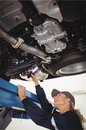 simsearch:6109-08782901,k - Female mechanic examining a car with flashlight Stock Photo - Premium Royalty-Free, Code: 6109-08952671