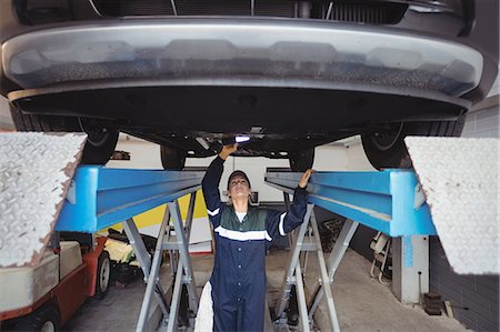 simsearch:6109-08952729,k - Female mechanic examining a car with flashlight Stock Photo - Premium Royalty-Free, Code: 6109-08952681