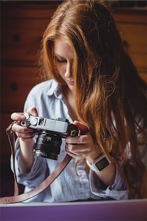 simsearch:6109-08953331,k - Woman looking at pictures on digital camera at home Stock Photo - Premium Royalty-Free, Code: 6109-08952771