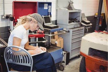 female mechanic - Female mechanic writing on notebook Foto de stock - Sin royalties Premium, Código: 6109-08952711