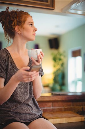 simsearch:6109-08764423,k - Thoughtful woman using mobile phone while having coffee Stock Photo - Premium Royalty-Free, Code: 6109-08952803