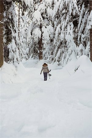 simsearch:6109-06195607,k - Female skier walking with ski on snowy landscape Photographie de stock - Premium Libres de Droits, Code: 6109-08953252