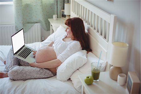 Pregnant woman using laptop on bed Photographie de stock - Premium Libres de Droits, Code: 6109-08953271
