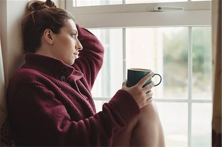 simsearch:6109-08953334,k - Thoughtful woman sitting at window sill and holding coffee cup Stockbilder - Premium RF Lizenzfrei, Bildnummer: 6109-08953347