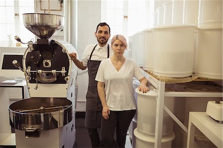 Male and female barista standing besides coffee grinding machine in coffee shop Stock Photo - Premium Royalty-Free, Code: 6109-08953359