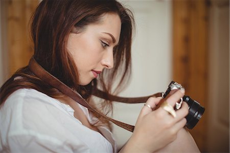 simsearch:6109-08953331,k - Woman looking at pictures on digital camera at home Stock Photo - Premium Royalty-Free, Code: 6109-08953332