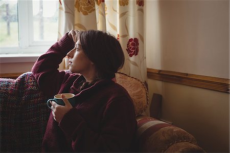 simsearch:6109-08944685,k - Thoughtful woman sitting and holding a coffee cup Stock Photo - Premium Royalty-Free, Code: 6109-08953338