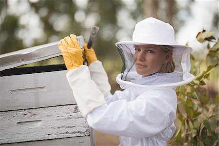 Portrait of female beekeeper opening honeycomb at apiary Foto de stock - Sin royalties Premium, Código: 6109-08953466