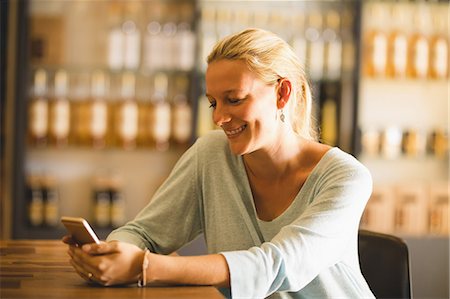 sales person with a tablet - Smiling saleswoman using mobile phone at table in supermarket Stock Photo - Premium Royalty-Free, Code: 6109-08953407