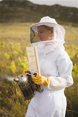 simsearch:400-08052054,k - Female beekeeper holding bee smoker and brush on farm Photographie de stock - Premium Libres de Droits, Code: 6109-08953417