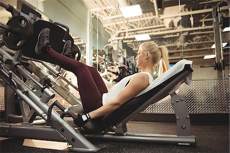 fingerless gloves - Fit woman exercising on a machine in the gym Photographie de stock - Premium Libres de Droits, Code: 6109-08953546