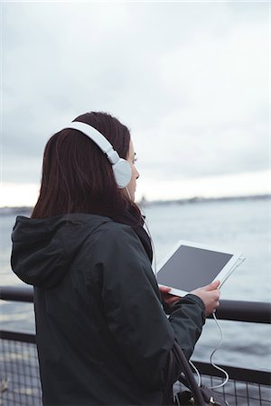 Rear view of woman using tablet while standing by railing against sky Photographie de stock - Premium Libres de Droits, Code: 6109-08953643