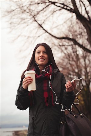 simsearch:6109-08689749,k - Smiling woman listening music on tablet while standing by illuminated tree Photographie de stock - Premium Libres de Droits, Code: 6109-08953647