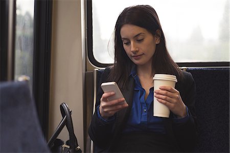 simsearch:614-06336113,k - Woman using mobile phone and holding coffee cup while sitting in train Stock Photo - Premium Royalty-Free, Code: 6109-08953646