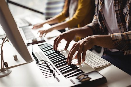 Mid section of audio engineers playing electric keyboard in recording studio Foto de stock - Sin royalties Premium, Código: 6109-08953667