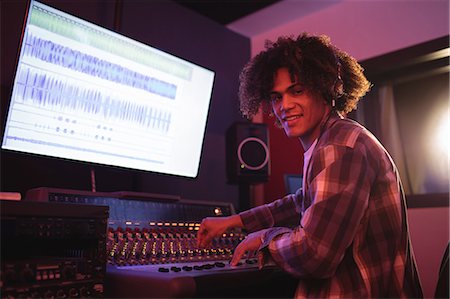 Portrait of male audio engineer using sound mixer in recording studio Foto de stock - Sin royalties Premium, Código: 6109-08953671