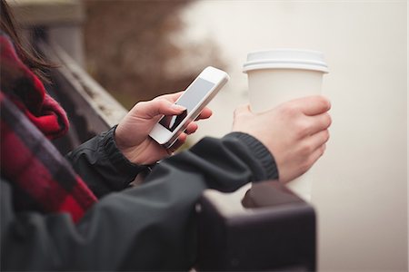 simsearch:6109-08481859,k - Cropped image of woman using mobile phone while holding disposable cup Stock Photo - Premium Royalty-Free, Code: 6109-08953614