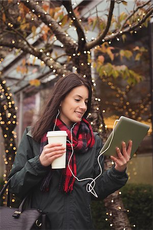 simsearch:6109-08689749,k - Happy woman listening music on tablet while standing by illuminated tree Photographie de stock - Premium Libres de Droits, Code: 6109-08953626