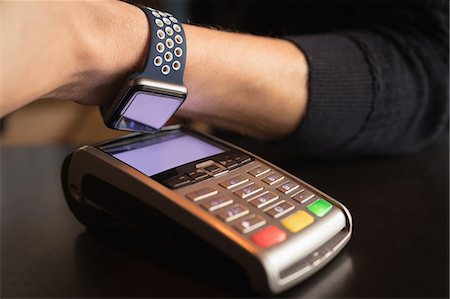 simsearch:6109-08953875,k - Close-up of man paying through smartwatch using NFC technology in Café Foto de stock - Sin royalties Premium, Código: 6109-08953874