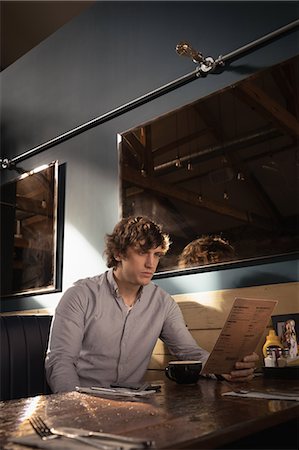 Man looking at menu card in restaurant Photographie de stock - Premium Libres de Droits, Code: 6109-08953892