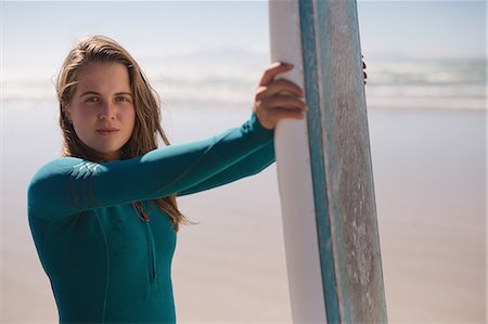 Portrait of female surfer standing on the beach with surfboard on a sunny day Stock Photo - Premium Royalty-Free, Code: 6109-08953983