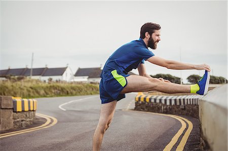 simsearch:6109-08928512,k - Handsome athlete stretching his leg on the road Stock Photo - Premium Royalty-Free, Code: 6109-08928448
