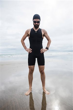 simsearch:6109-08928512,k - Athlete in swimming goggles standing with hand on hip at beach Stock Photo - Premium Royalty-Free, Code: 6109-08928454