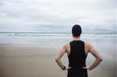 simsearch:6109-08928512,k - Athlete in swimming costume standing with hand on hip at beach Stock Photo - Premium Royalty-Free, Code: 6109-08928459