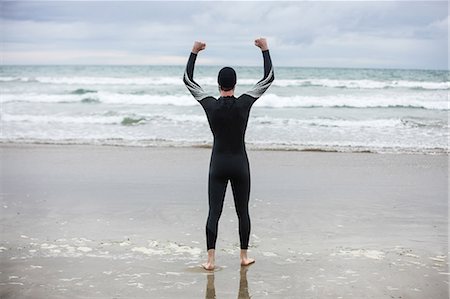 simsearch:6109-08928512,k - Rear view of athlete in wet suit standing with arms up on beach Stock Photo - Premium Royalty-Free, Code: 6109-08928463