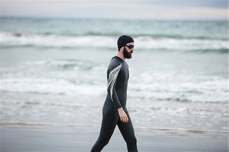 simsearch:6109-08928512,k - Handsome athlete in wet suit walking on beach Stock Photo - Premium Royalty-Free, Code: 6109-08928461