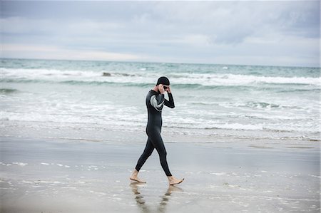 simsearch:6109-08928512,k - Athlete in wet suit wearing swimming goggles while walking on the beach Stock Photo - Premium Royalty-Free, Code: 6109-08928462
