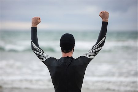 simsearch:6109-08928512,k - Rear view of athlete in wet suit standing with arms up on beach Stock Photo - Premium Royalty-Free, Code: 6109-08928464