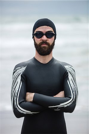 simsearch:6109-08928446,k - Athlete in wet suit standing with his arms crossed on beach Photographie de stock - Premium Libres de Droits, Code: 6109-08928468