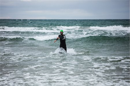 simsearch:6118-08399557,k - Athlete in wet suit running in the sea Stock Photo - Premium Royalty-Free, Code: 6109-08928482
