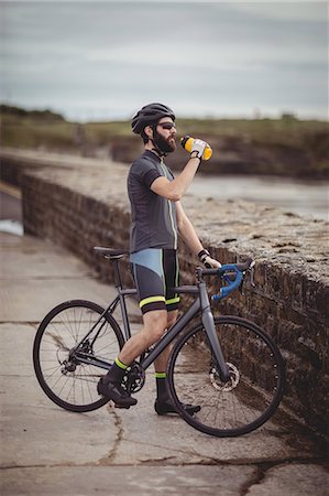 Athlete refreshing from bottle while riding a bicycle on the road Stock Photo - Premium Royalty-Free, Code: 6109-08928544