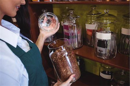 simsearch:6109-08928615,k - Mid section of female shopkeeper holding a jar of spice in shop Photographie de stock - Premium Libres de Droits, Code: 6109-08928575