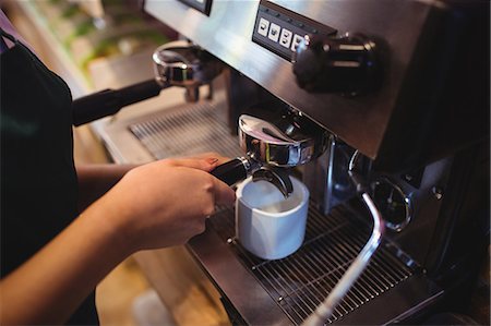 simsearch:6109-08829857,k - Close-up of waitress taking coffee from espresso machine in cafeteria Foto de stock - Royalty Free Premium, Número: 6109-08928579