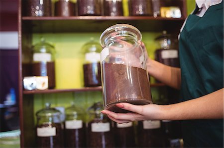 spice merchant - Mid section of female shopkeeper holding a jar of spice in shop Stock Photo - Premium Royalty-Free, Code: 6109-08928582