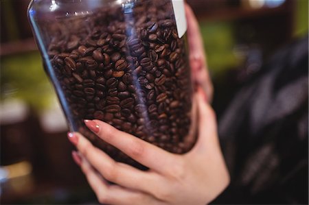 simsearch:6109-08928615,k - Close-up of woman holding jar of coffee beans at counter in shop Photographie de stock - Premium Libres de Droits, Code: 6109-08928593