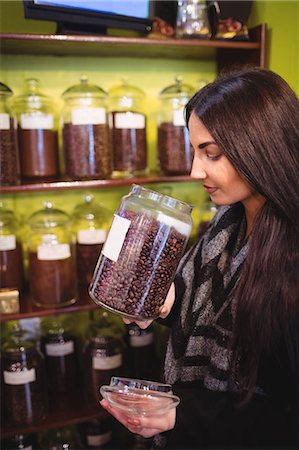 simsearch:6109-08928615,k - Beautiful woman smelling jar of coffee beans in shop Photographie de stock - Premium Libres de Droits, Code: 6109-08928591