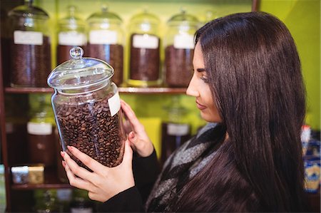 simsearch:6109-08928615,k - Beautiful woman holding jar of coffee beans at counter in shop Photographie de stock - Premium Libres de Droits, Code: 6109-08928592