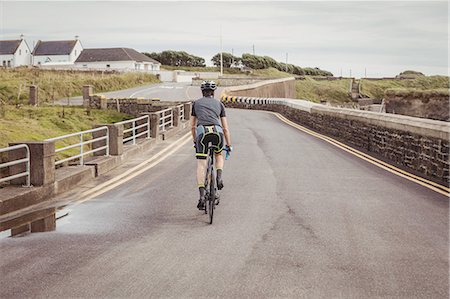 simsearch:6109-08764763,k - Rear view of athlete riding a bicycle on the road Stock Photo - Premium Royalty-Free, Code: 6109-08928533