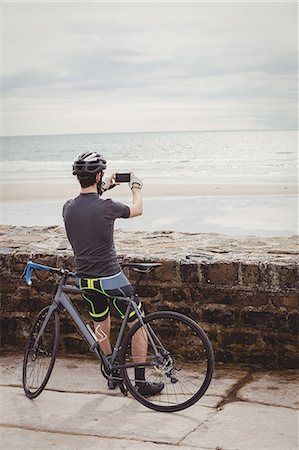 simsearch:6109-08928555,k - Rear view of athlete clicking a picture from his smartphone while resting on his bicycle Photographie de stock - Premium Libres de Droits, Code: 6109-08928532