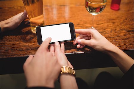 simsearch:6109-08945043,k - Close-up of couple using mobile phone at bar counter Foto de stock - Sin royalties Premium, Código: 6109-08928642