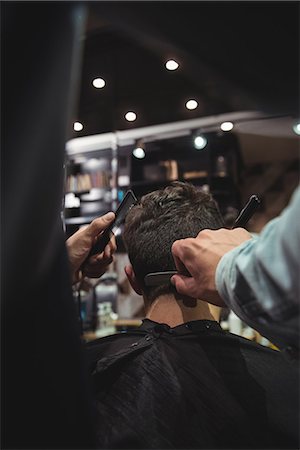Man getting his hair trimmed with razor in baber shop Foto de stock - Sin royalties Premium, Código: 6109-08928777