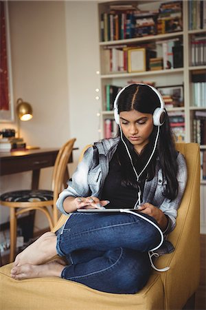 Woman listening to music with headphones and digital tablet in living room at home Stock Photo - Premium Royalty-Free, Code: 6109-08928703
