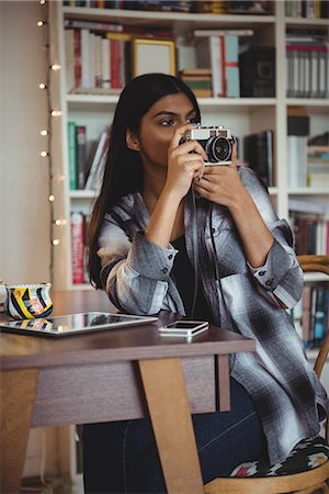 Woman clicking photo from camera in living room at home Stock Photo - Premium Royalty-Free, Code: 6109-08928707