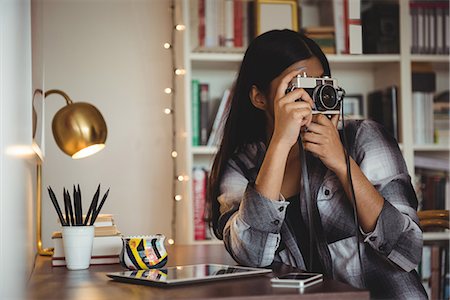Woman clicking photo from camera in living room at home Stock Photo - Premium Royalty-Free, Code: 6109-08928706