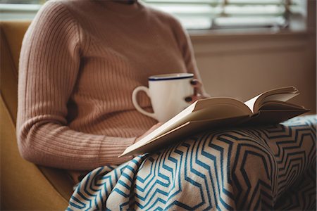 simsearch:6109-08944595,k - Woman reading book while having coffee in living room at home Photographie de stock - Premium Libres de Droits, Code: 6109-08928723